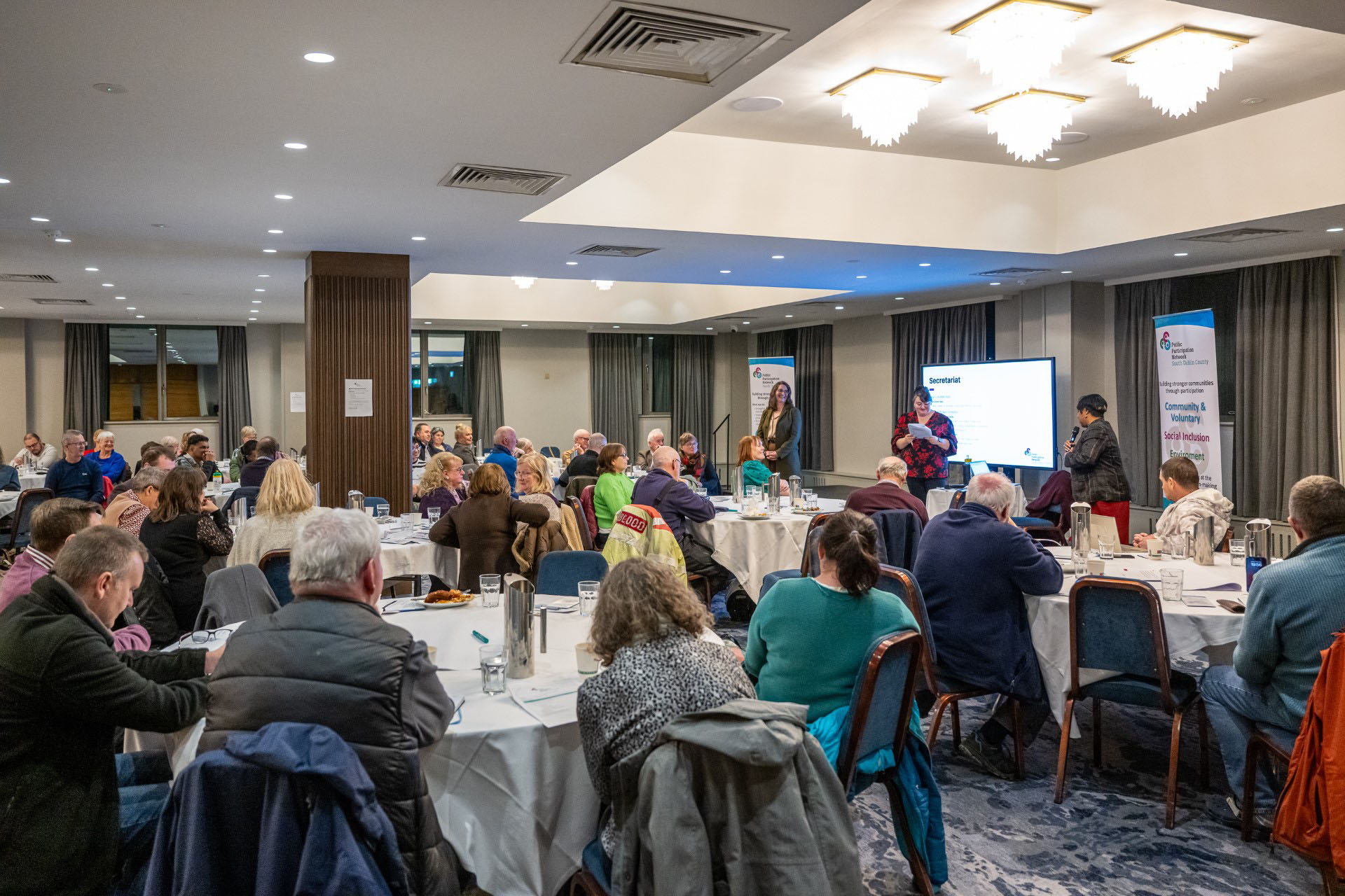 Wide room view of PPN Plenary with multiple tables of participants, Plaza Hotel, Tallaght