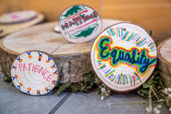 Painted wooden discs with words Equality, Happiness and Patience displayed on wood slices