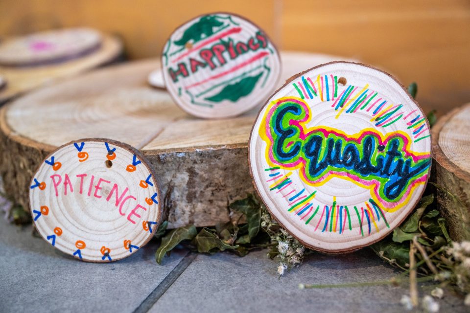 Painted wooden discs with words Equality, Happiness and Patience displayed on wood slices