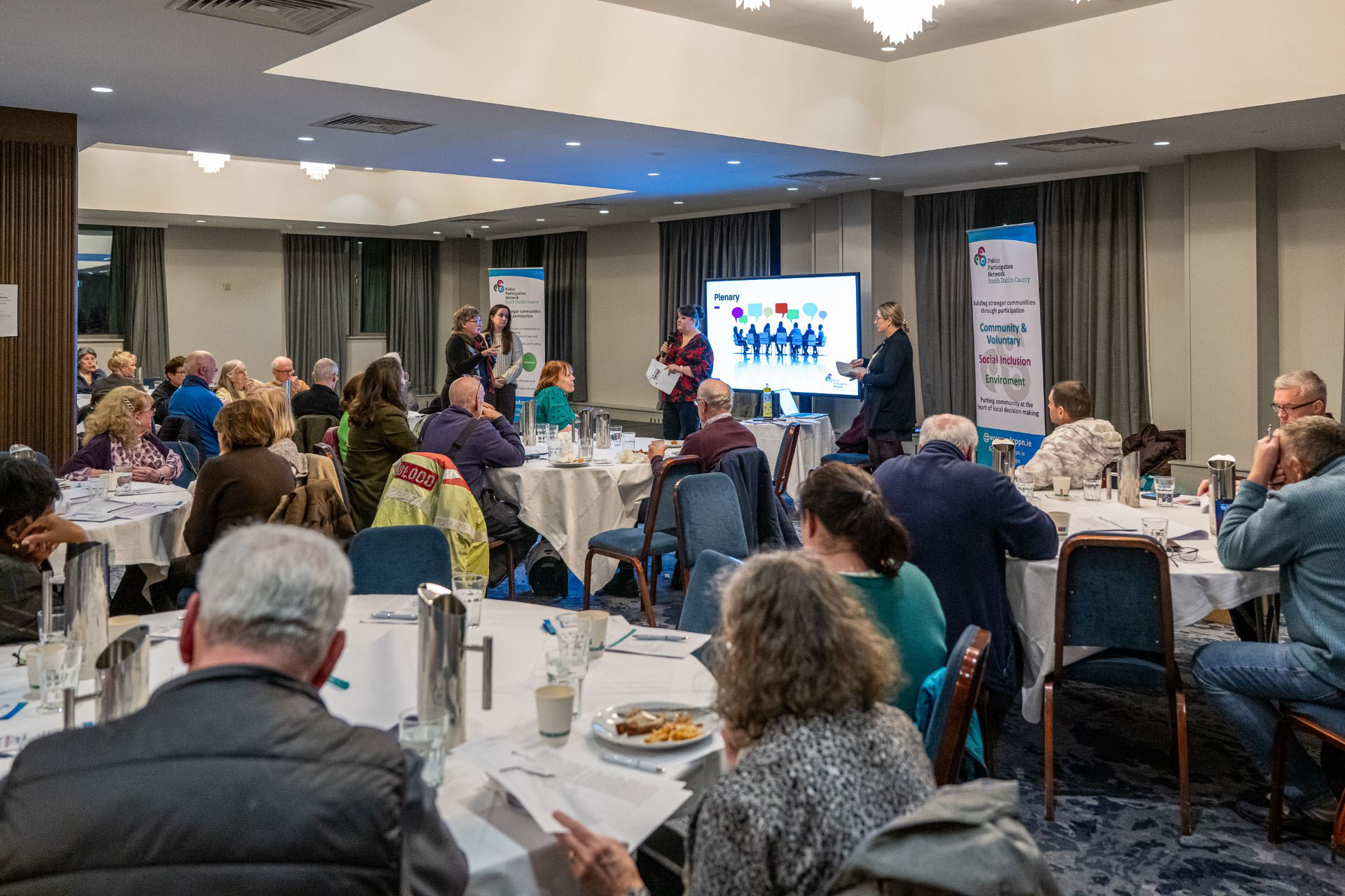 Plenary session in progress with speakers and attendees reviewing papers, Plaza Hotel, Tallaght