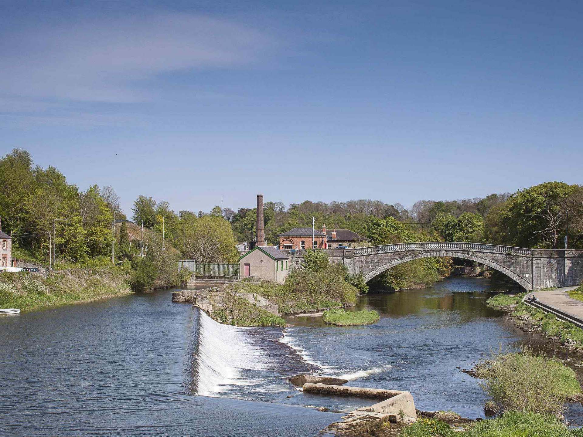 Stone bridge and weir on the River Liffey in Lucan with historic riverside buildings