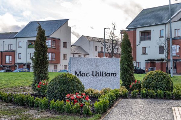Stone sign reading “Mac Uilliam” within landscaped planting at a housing development in South Dublin County
