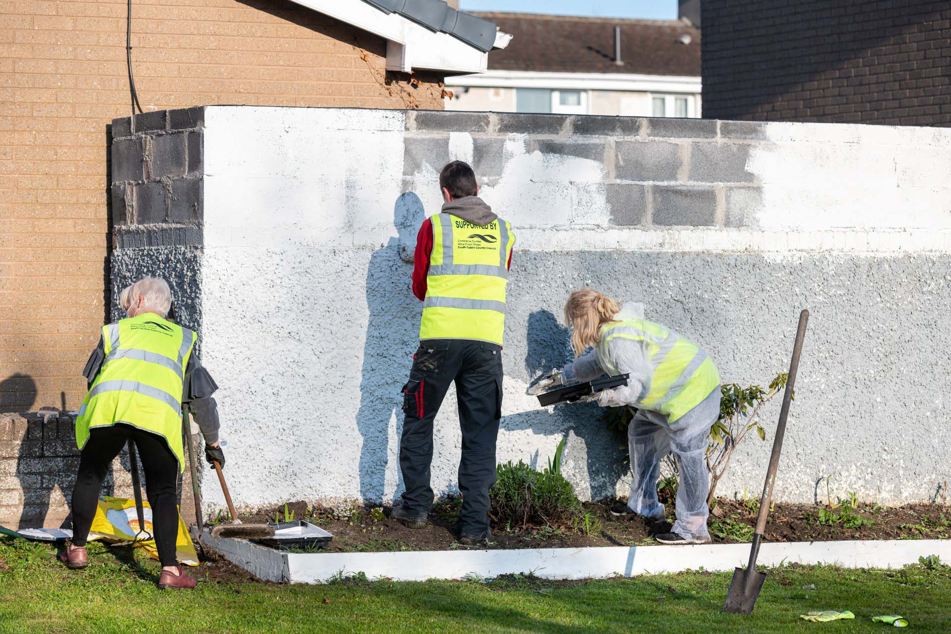 Volunteers in high-vis vests planting and painting during a community planting day at Lealand