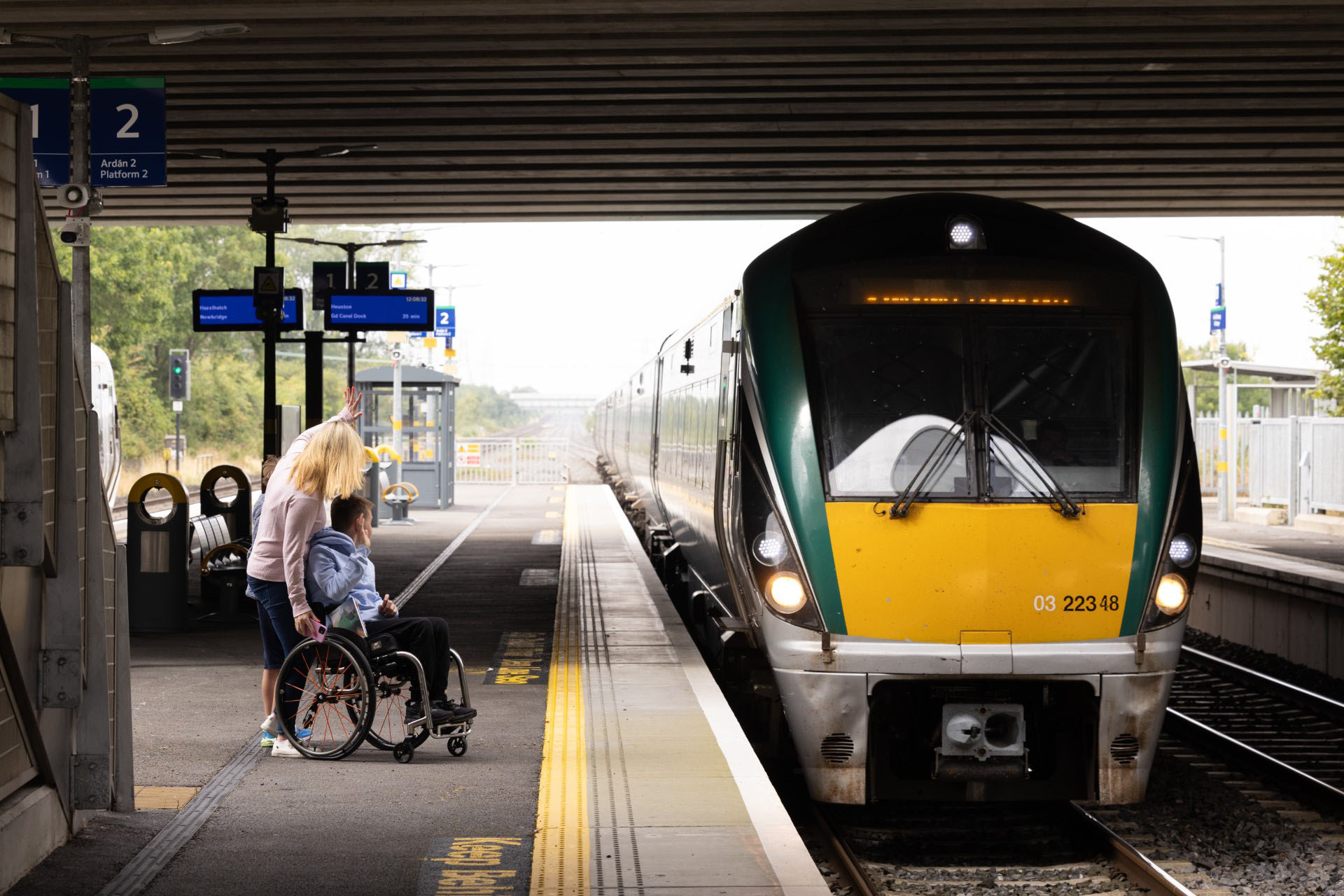 Wheelchair user and companion on a train platform as a commuter train arrives in South Dublin County